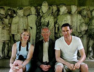 In front of a stone frieze showing Queen Elizabeth and her court.